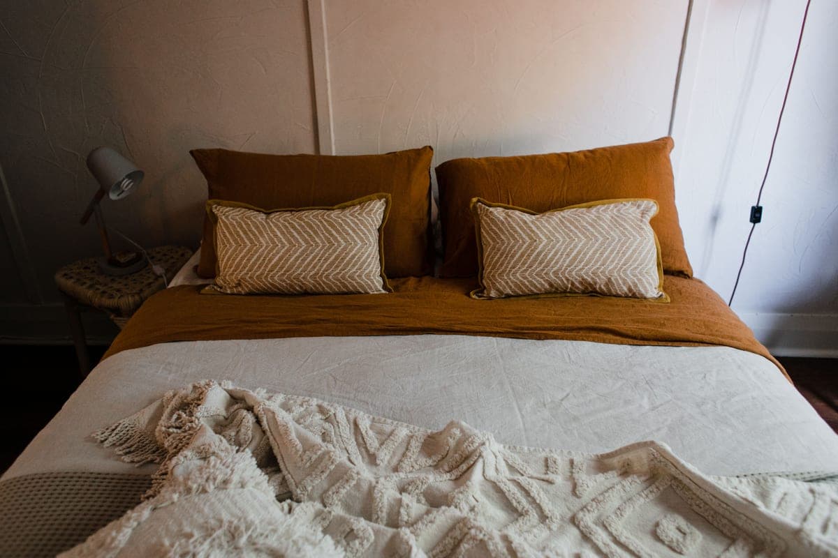 A made bed with neutral bedding in a quiet bedroom