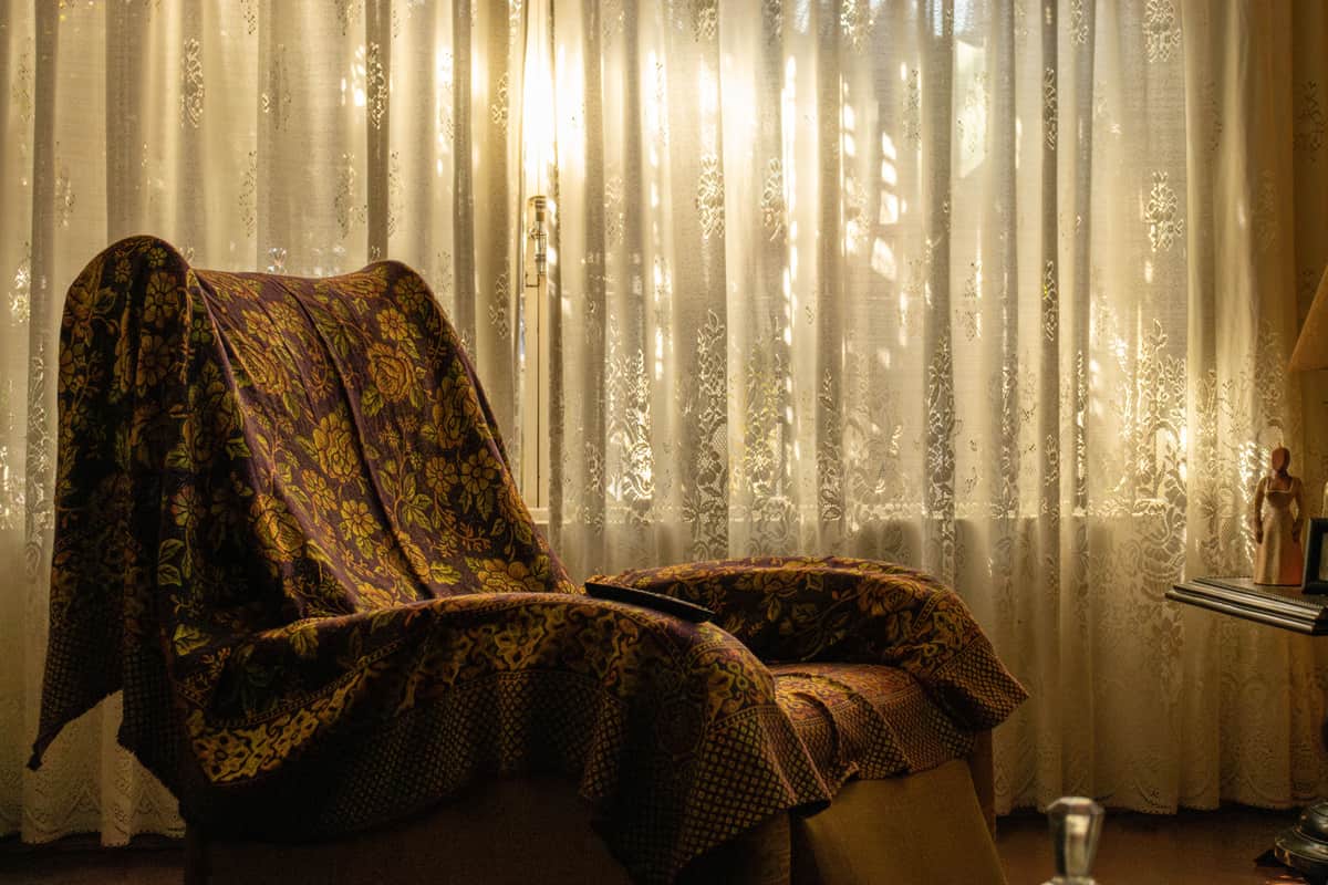 A blanket draped over an armchair beside a reading lamp