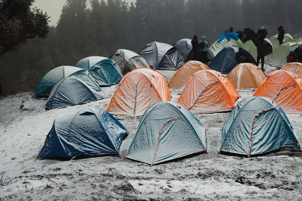 A tent lit from inside at night on cold ground