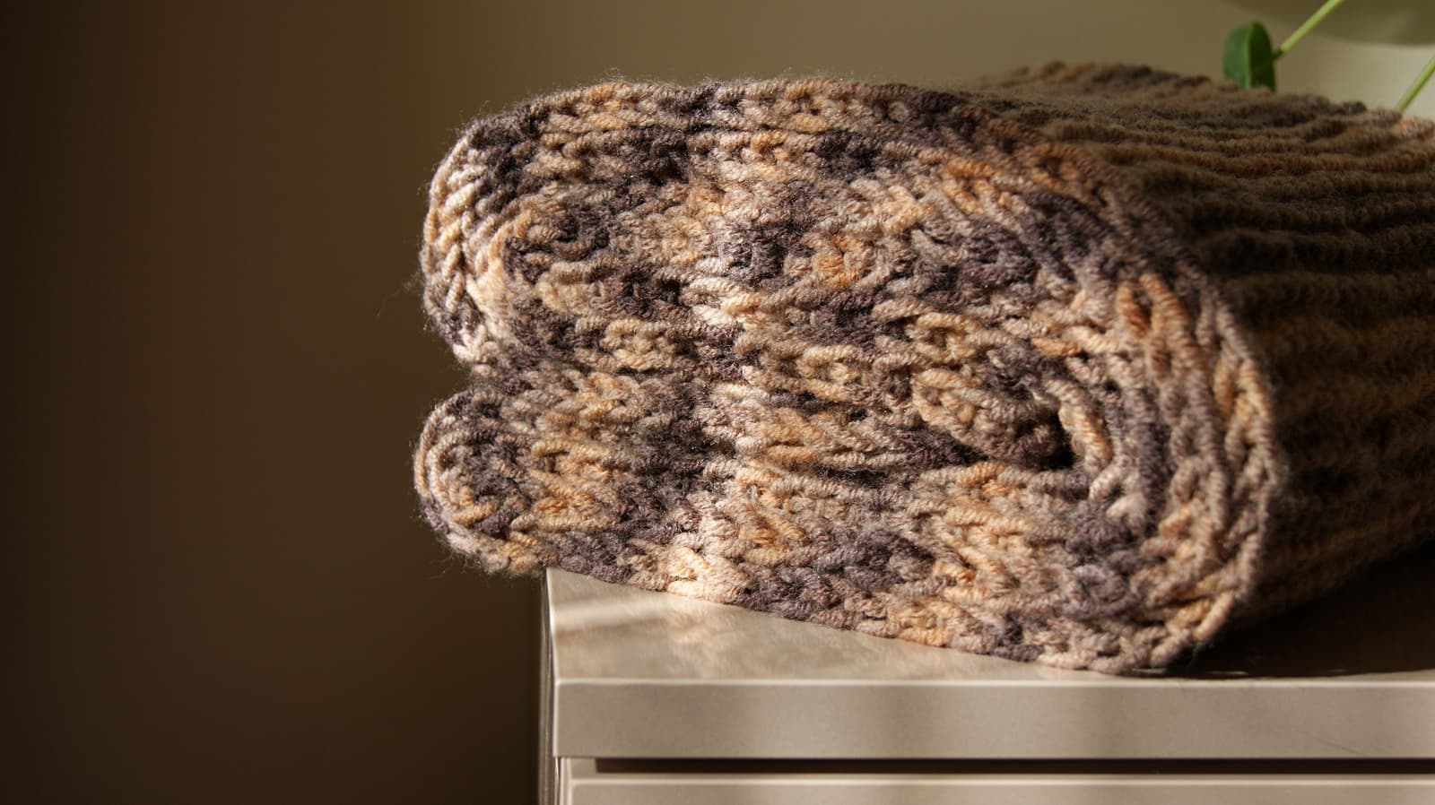 A folded wool blanket on a bed in low winter light