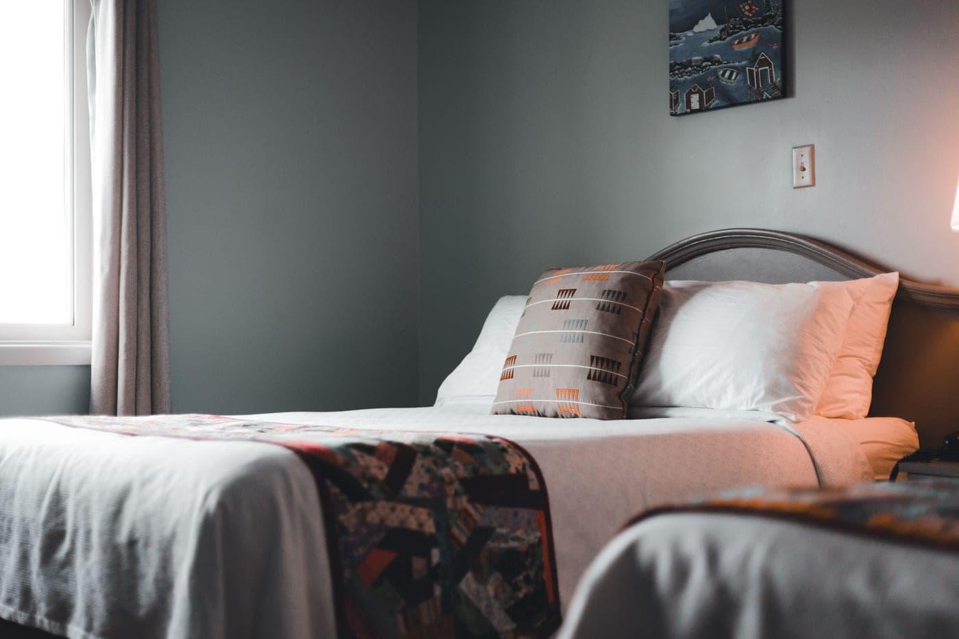 A made bed with a heavy blanket folded back, in low winter light